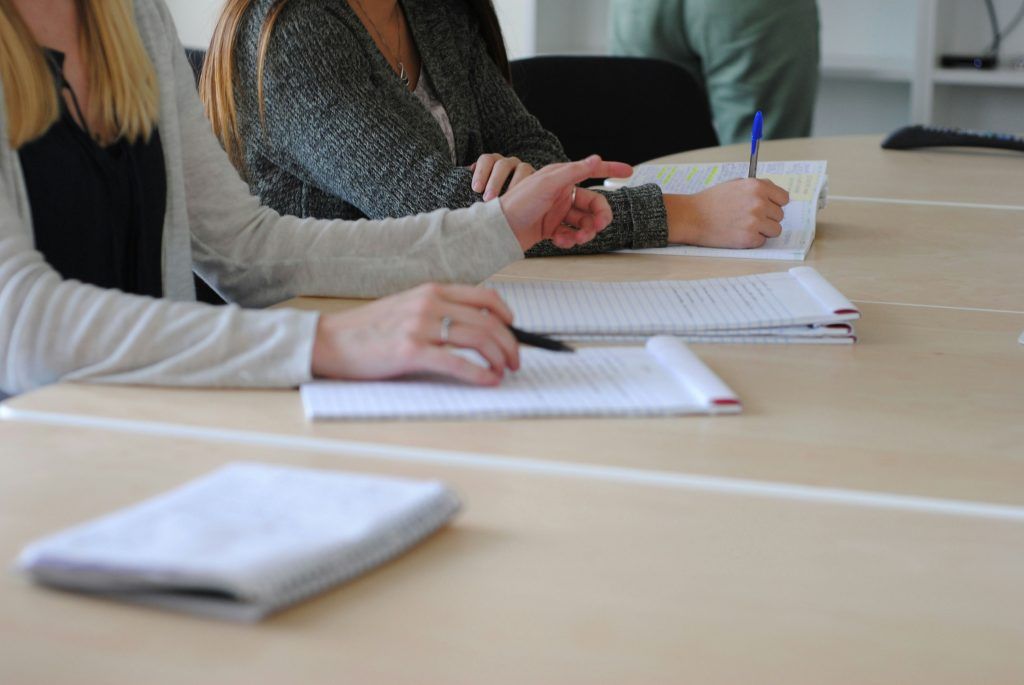 two people collaborating and taking notes in notebooks