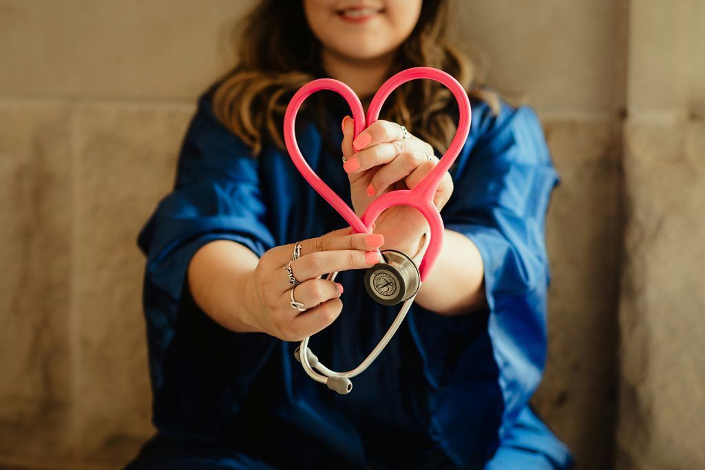 a health professional holding a pink stethoscope shaped into a heart