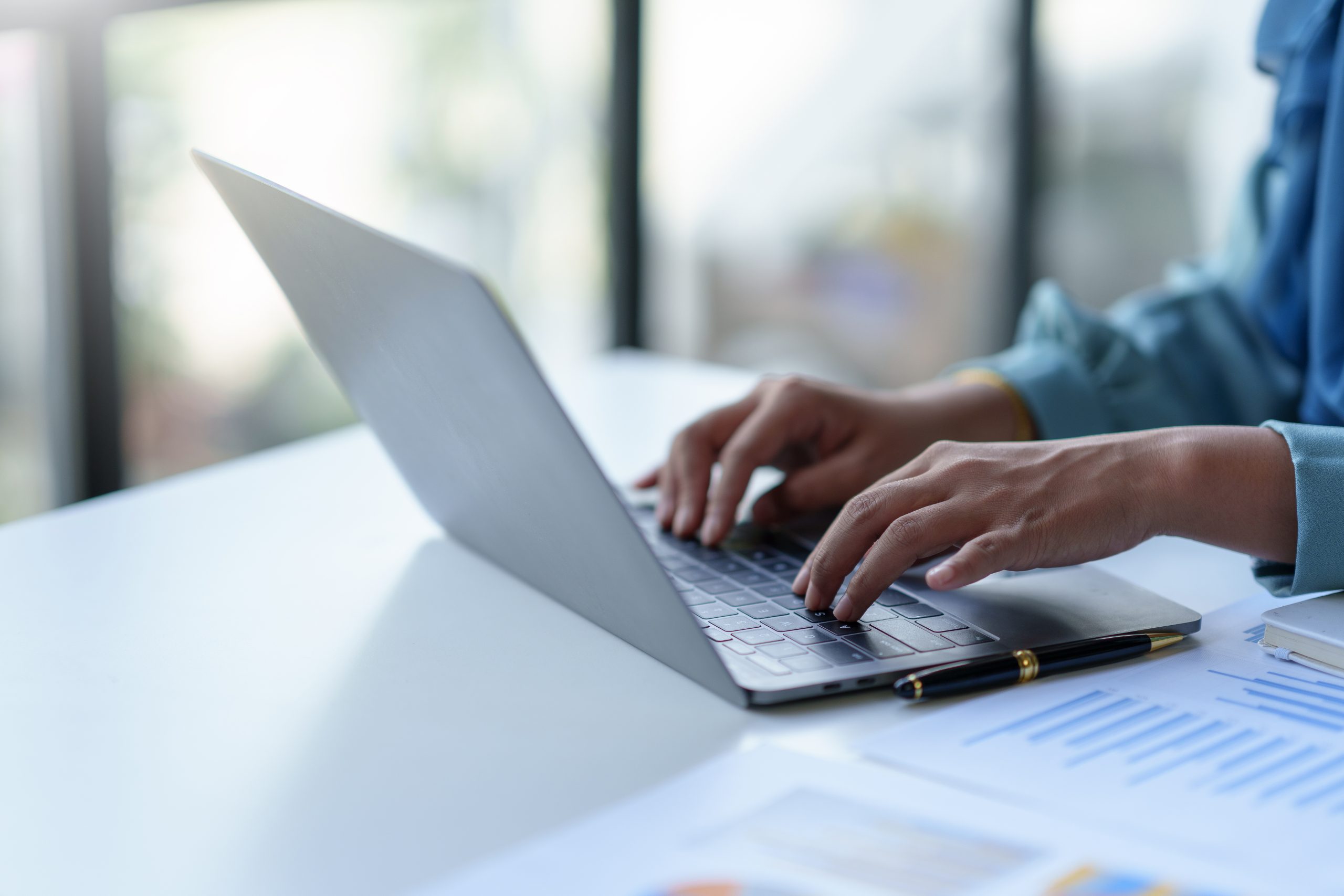 Close-up of a business woman typing a laptop computer on a desk in the office.